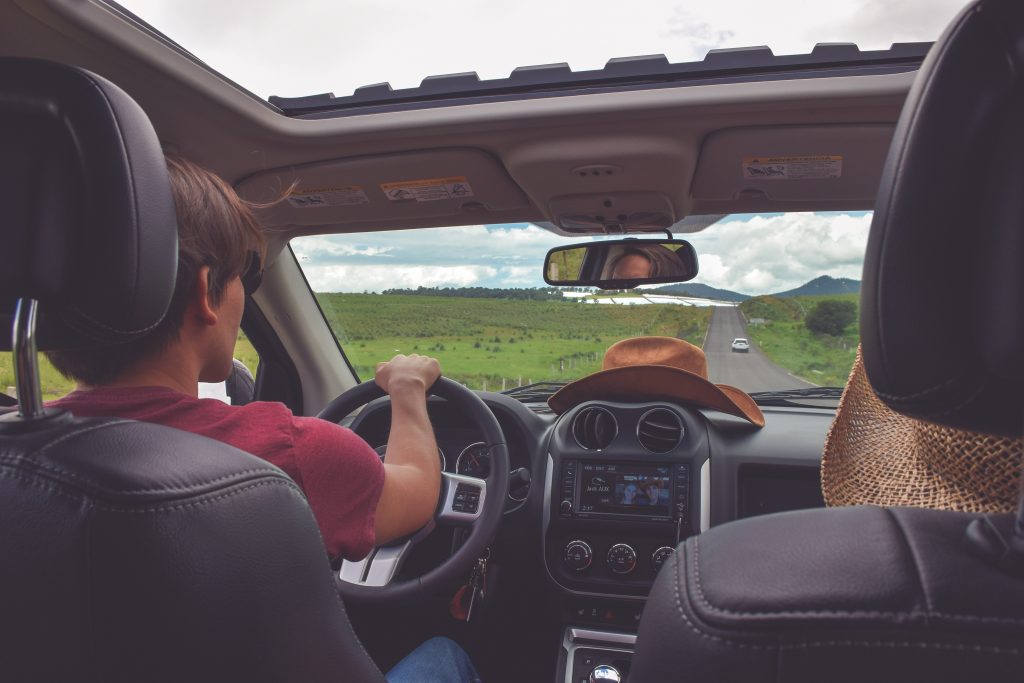 backseat view of 2 teens driving down country road